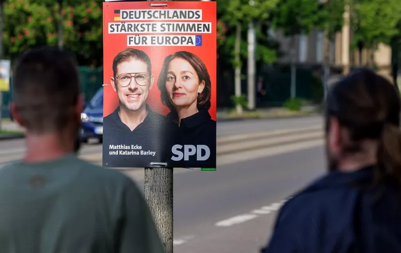Pedestrians walk past an election poster showing Germany's Social Democratic Party SPD lead candidates Matthias Ecke (L) and Katarina Barley for the upcoming European Parliament elections along Schandauer Strasse in the city district Striesen of Dresden, eastern Germany on May 4, 2024. German Chancellor Scholz on May 4 condemned an attack on one of his party's European Parliament deputies as a "threat" to democracy after authorities said a political motive was suspected. Police said four unknown attackers beat up Matthias Ecke, an MEP for the Social Democratic Party (SPD), as he put up EU election posters in the eastern city of Dresden on Friday night, May 3. Ecke, 41, was "seriously injured" and required an operation after the attack, his party said. Police confirmed he needed hospital treatment. (Photo by JENS SCHLUETER / AFP)