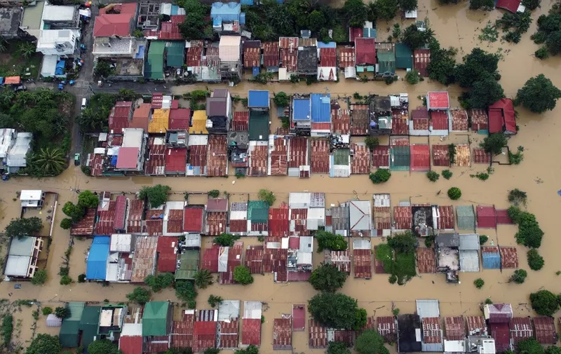 An aerial view shows flood-inundated houses at Capitol Hills in Alibagu, Ilagan city, Isabela province on October 31, 2022, after Tropical Storm Nalgae hit the region. - The death toll from a storm that battered the Philippines has jumped to 98, the national disaster agency said October 31, with little hope of finding survivors in the worst-hit areas. (Photo by AFP)