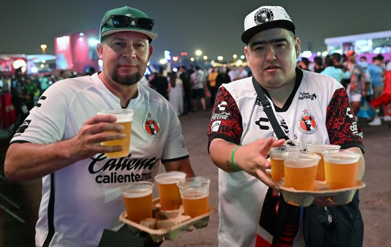 Men enjoy a beer during the FIFA Fan Festival opening day at Al Bidda park in Doha on November 19, 2022, ahead of the Qatar 2022 World Cup football tournament. (Photo by Glyn KIRK / AFP)