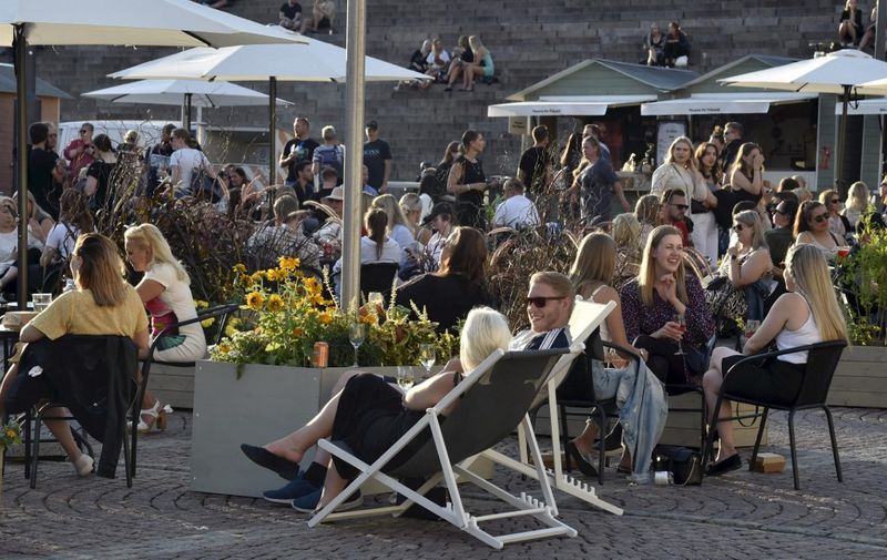 People enjoy meals and drinks on a large open-air food court in the centrally-located Senate Square in Helsinki, Finland, late on July 17, 2020, the first Friday after lifting the COVID-related restrictions. - The restrictions concerning the opening hours, licensing hours and numbers of customers of food and beverage service businesses were lifted completely from 13 July 2020. All customers are still required to have their own seats. In addition, food and beverage service businesses must continue to provide their customers with instructions on how to prevent the spread of the COVID-19 coronavirus. (Photo by Jussi Nukari / Lehtikuva / AFP) / Finland OUT