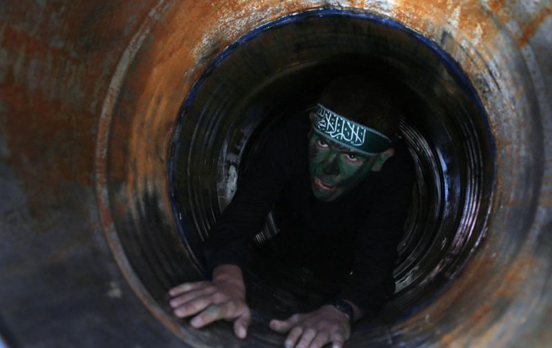 A Palestinian youth crawls in a tunnel during a graduation ceremony for a training camp run by the Hamas movement on January 29, 2015 in Khan Yunis, in the southern Gaza Strip.  AFP PHOTO / SAID KHATIB (Photo by SAID KHATIB / AFP)
