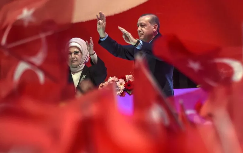 Turkish President Recep Tayyip Erdogan (R) and his wife Emine Erdogan (L) flash the four-finger "Rabia sign" during a campaign rally of Turkey's president on April 12, 2017 during a 15 July Martyrs meeting and a campaign rally for the "yes" vote in a constitutional referendum in Istanbul.
Turks will vote on April 16, 2017 on whether to change the current parliamentary system into an executive presidency. / AFP PHOTO / Ozan KOSE