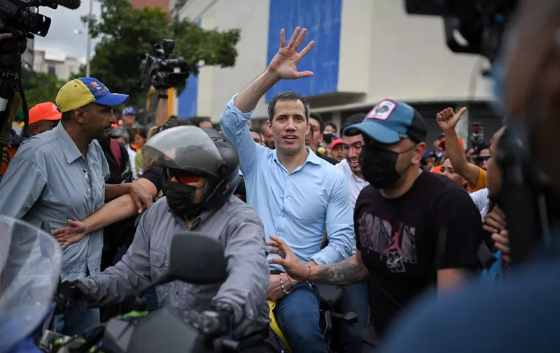 Venezuelan opposition leader Juan Guaido (C) waves while leaving a demonstration to demand a date for presidential elections, in Caracas on October 27, 2022. (Photo by Federico PARRA / AFP)