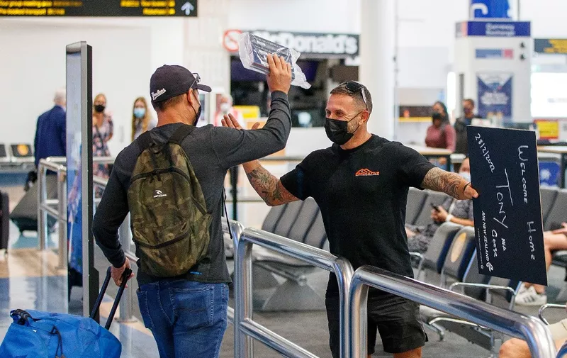 Passengers and loved ones reunite at the arrivals hall on the first day of New Zealanders returning from Australia after the border reopened for travellers observing home self-isolation rules, at the Auckland international airport on February 28, 2022. (Photo by DAVID ROWLAND / AFP)
