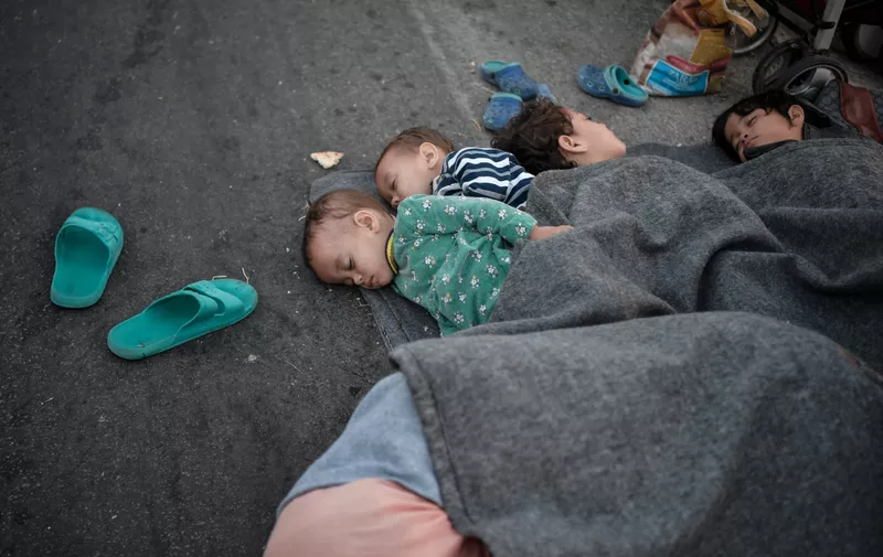 Children rest as they spend the night on the road near Mytilene after a fire destroyed Greece's largest Moria refugee camp on the island of Lesbos, early on September 10, 2020. Greek authorities on September 10 were racing to shelter thousands of asylum seekers left homeless on Lesbos after the island's main migrant camp was gutted by back-to-back fires, which destroyed the official part of the camp housing 4,000 people. Another 8,000 lived in tents and makeshift shacks around the perimeter and many were badly damaged.,Image: 557181372, License: Rights-managed, Restrictions: , Model Release: no