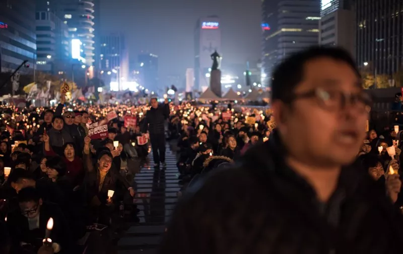 Demonstrators shout slogans and hold candles during an anti-government protest in Gwanghwamun square in central Seoul on November 19, 2016.
Up to half-a-million protestors were expected to take to the streets of Seoul for the fourth week in a row, demanding President Park Geun-Hye resign over a corruption scandal. / AFP PHOTO / Ed JONES