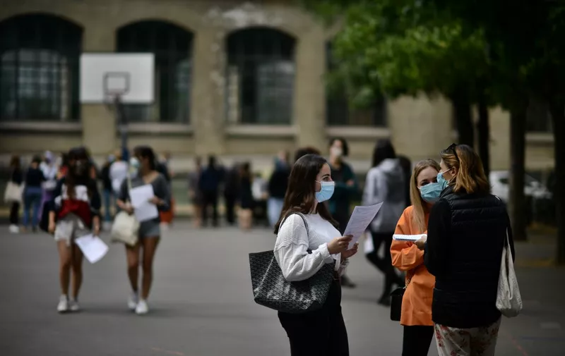 Pupils wearing masks talk in the courtyard as they arrive to learn the outcome of the baccalaureate at the Jean-de-La-Fontaine highschool in the 16th arrondissement of Paris on July 7, 2020. (Photo by Martin BUREAU / AFP)