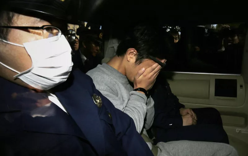 Suspect Takahiro Shiraishi (C) covers his face with his hands as he is transported to the prosecutor's office from a police station in Tokyo on November 1, 2017. - The 27-year-old Japanese man, who was arrested after police found nine dismembered corpses rotting in his house, has confessed to killing all his victims over a two-month spree after contacting them via Twitter, media reports. (Photo by STR / JIJI PRESS / AFP) / Japan OUT