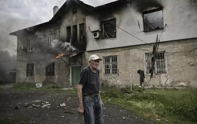 An eldery man stands in front of the apartment building where he lives, as it is burning after a shelling in the city of Lysychansk, in the eastern Ukrainian region of Donbas, on June 5, 2022. (Photo by ARIS MESSINIS / AFP)