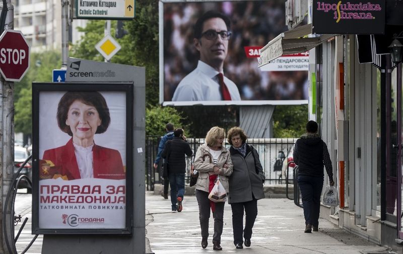 People walk past electoral posters of presidential candidates Stevo Pendarovski (R) from the ruling SDSM party and Gordana Siljanovska from the Vmro Domn opposition party in Skopje on April 18, 2019, ahead of April 21 presidential election. - North Macedonia holds the first round of its presidential election on April 21, the country's first vote under a new name as it struggles with enduring economic problems, cronyism and corruption. The vote for the largely ceremonial post comes less than three months after a deal with Athens on Skopje's name change came into force, ending a decades-long identity dispute between the neighbours. (Photo by Robert ATANASOVSKI / AFP)