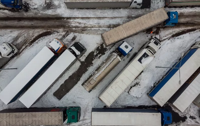 This aerial view shows Ukrainian trucks on the parking lot next to Korczowa Polish-Ukrainian border crossing, on December 5, 2023. In a Polish car park near the Ukrainian border, truck drivers stranded by a month-long blockade that has caused disruption and a row with Ukraine shoveled snow off their vehicles.
Around 100 truckers have been stuck in Korczowa, one of the crossings blocked by protesting Polish hauliers who complain about what they say is unfair competition from Ukrainian companies. (Photo by Wojtek Radwanski / AFP)