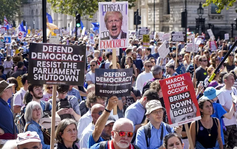 Demonstrators hold up placards in the sunshine at a protest against the move to suspend parliament in the final weeks before Brexit outside Downing Street in London on August 31, 2019. - Demonstrations, being dubbed "Stop The Coup" by organisers, were to be held across Britain on August 31 against Prime Minister Boris Johnson's move to suspend parliament in the final weeks before Brexit. The protests come ahead of an intense political week in which Johnson's opponents will seek to block the move in court and legislate against a no-deal departure from the European Union. (Photo by Niklas HALLE'N / AFP)