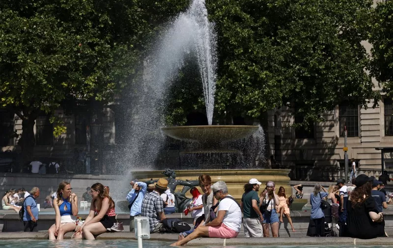 People cool off beside the fountains in Trafalgar Square in central London on June 17, 2022, on what is expected to be the hottest day of the year so far in the capital. - A Level 3 Heat-Health alert for London, the East of England and the South East has been announced to help protect health services, the UK Health Security Agency (UKHSA) has said, Friday. (Photo by CARLOS JASSO / AFP)