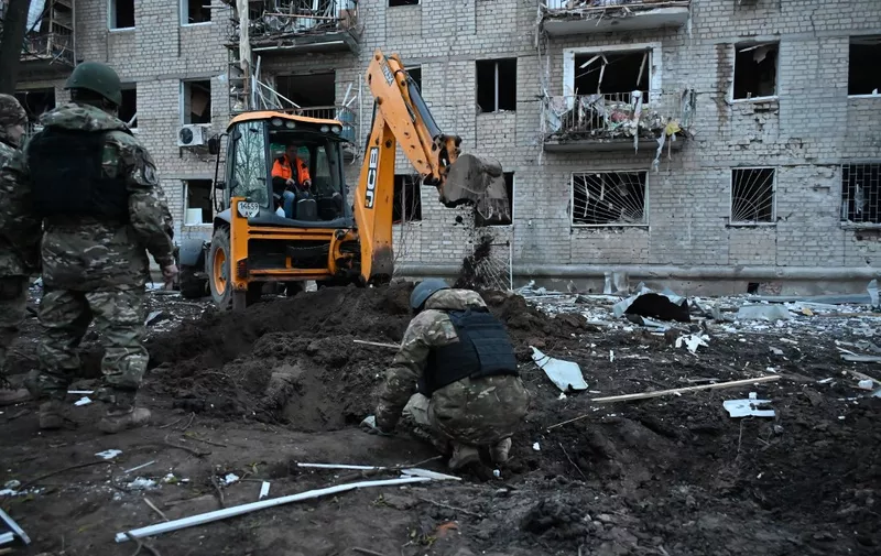 Ukrainian law enforcement officers examine debris outside a residential building damaged as a result of Russian strikes in Kharkiv on March 27, 2024, amid Russian invasion in Ukraine. In Ukraine's second largest city Kharkiv, which has been reeling from power outages due to the strikes, officials said aerial bombing and shelling killed at least one person and injured 18 others. (Photo by SERGEY BOBOK / AFP)
