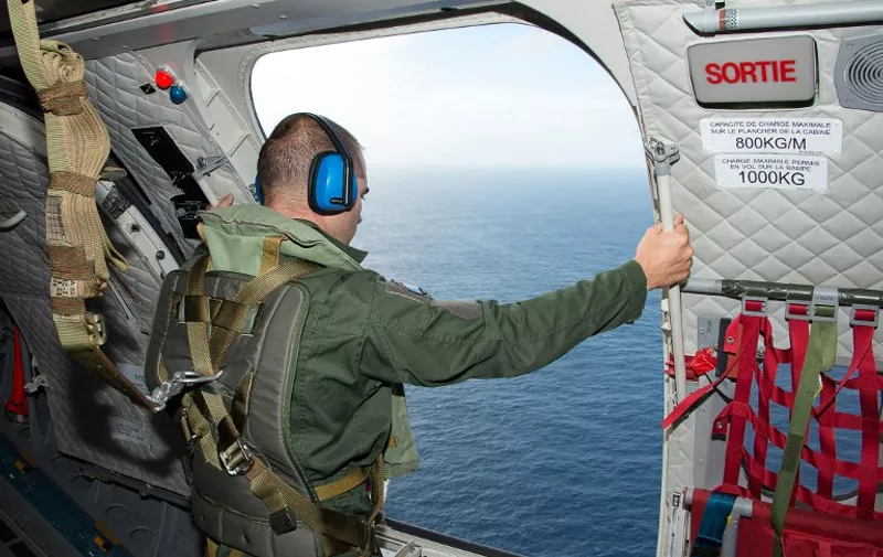 This handout picture taken and released by the ECPAD (French Defense Audiovisual Communication and Production Unit) on August 7, 2015 shows a French servicemen looking out from an open door of an aircraft over the Indian Ocean, off the French overseas island of La Reunion, during searches for more wreckage of the Malaysia Airlines flight MH370, which went missing over the Indian Ocean on March 8, 2014. France launched a hunt for more wreckage from the ill-fated MH370 plane off Reunion island on August 7 in a fresh effort to shed light on one of aviation's biggest mysteries. The tiny French Indian Ocean territory has been under intense scrutiny since a beach cleaner found a washed-up wing part last week, which Malaysian Prime Minister Najib Razak later declared was part of the Boeing 777 that mysteriously vanished 17 months ago.  AFP PHOTO / ECPAD / PATRICK BECOT
==RESTRICTED TO EDITORIAL USE - MANDATORY CREDIT "AFP PHOTO / ECPAD / PATRICK BECOT" - NO MARKETING NO ADVERTISING CAMPAIGNS - DISTRIBUTED AS A SERVICE TO CLIENTS - NO ARCHIVE - TO BE USED WITHIN 30 DAYS FROM 07/08/2015==