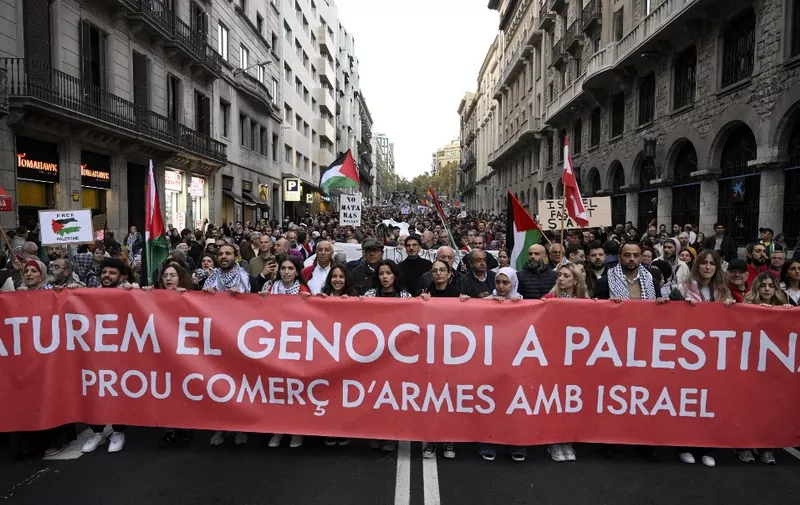 Demonstrators carry a banner reading "Let's stop the genocide in Palestine. Enough arms trade with Israel." during a demonstration in support of the Palestinian people, in Barcelona on November 11, 2023. Thousands of civilians, both Palestinians and Israelis, have died since October 7, 2023, after Palestinian Hamas militants based in the Gaza Strip entered southern Israel in an unprecedented attack triggering a war declared by Israel on Hamas with retaliatory bombings on Gaza. (Photo by Josep LAGO / AFP)