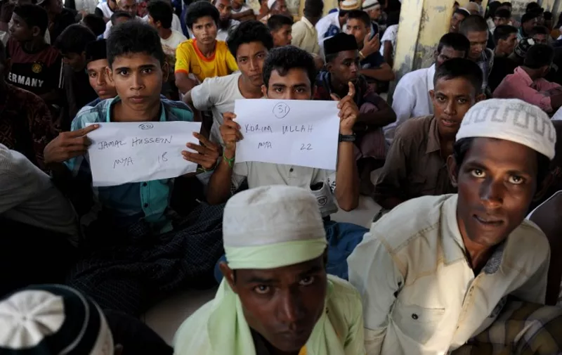 Rescued Myanmarese, part of a group of mostly Rohingyas from Myanmar and Bangladesh, prepare for a photographic identification procedure by an Indonesian immigration official following their arrival at the fishing town of Kuala Cangkoi in Aceh province on May 13, 2015, after the migrants numbering nearly 600 were relocated by Indonesian authorities from a government sports stadium. Malaysia joined Indonesia on May 13 in vowing to turn back vessels bearing a wave of migrants, drawing warnings that the hardline policy could be a death sentence for boatloads of people at risk of starvation and disease. AFP PHOTO / CHAIDEER MAHYUDDIN