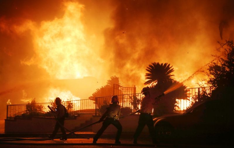 PORTER RANCH, CALIFORNIA - OCTOBER 11: Firefighters work at a house fire in the early morning hours during the Saddleridge Fire on October 11, 2019 in Porter Ranch, California. The fast moving wind-driven fire has burned more than 7,500 acres and destroyed 25 structures.   Mario Tama/Getty Images/AFP