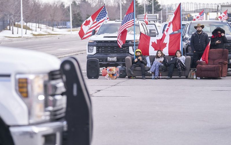 Protestors against Covid-19 vaccine mandates sit on a couch as the group blocks the roadway at the Ambassador Bridge border crossing in Windsor, Ontario, Canada on February 9, 2022. - The protestors, who are in support of the Truckers Freedom Convoy in Ottawa, have blocked traffic in the Canada bound lanes from the bridge since Monday evening. Approximately $323 million worth of goods cross the Windsor-Detroit border each day at the Ambassador Bridge making it North Americas busiest international border crossing. (Photo by Geoff Robins / AFP)