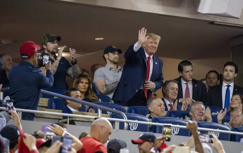 US President Donald Trump (C) waves as US First Lady Melania Trump looks on as they watch Game 5 of the World Series between the Washington Nationals and Houston Astros at Nationals Park in Washington, DC on October 27, 2019. (Photo by TASOS KATOPODIS / AFP)