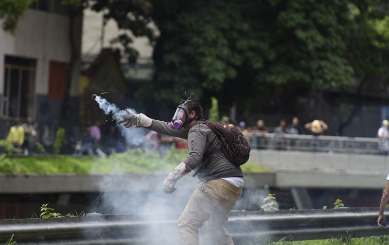 A man protesting against new emergency powers decreed this week by President Nicolas Maduro clashes with policemen in Caracas on May 18, 2016. 
Public outrage was expected to spill onto the streets of Venezuela Wednesday, with planned nationwide protests marking a new low point in Maduro's unpopular rule. / AFP PHOTO / JUAN BARRETO