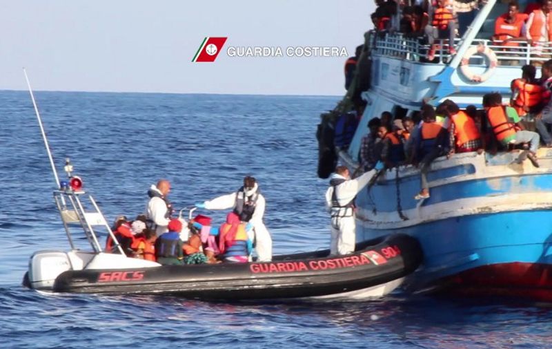 In this video grab released by the Italian Coast Guards (Guardia Costiera) on August 23, 2015 migrants waiting on an overcrowded boat being helped during a rescue operation off the coast of Libya as part of the Frontex-coordinated Operation Triton. Italy's coastguard coordinated the rescue of 4,400 migrants from boats in the Mediterranean in a single day on August 22, 2015, officials said. Saturday's total was thought to be the highest for a single day in recent years as calm conditions encouraged people smugglers to leave Libya with boats stuffed with as many paying passengers on board as possible. The coastguard said it had received distress calls from a total of 22 vessels, either inflatable dinghies or wooden former fishing boats -- all of them dangerously overcrowded and many of them lacking basic safety equipment. AFP PHOTO / HO
= RESTRICTED TO EDITORIAL USE - MANDATORY CREDIT "AFP PHOTO / GUARDIA COSTIERA" - NO MARKETING NO ADVERTISING CAMPAIGNS - DISTRIBUTED AS A SERVICE TO CLIENTS =