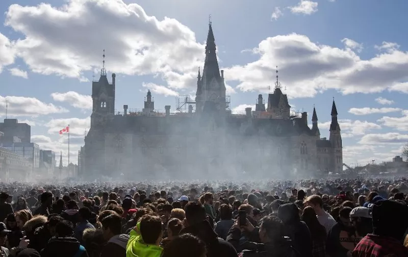 (FILES) In this file photo taken on April 20, 2018 Smoke lingers over Parliament Hill as people smoke marijuana during the annual 4/20 rally on Parliament Hill in Ottawa, Ontario. - Canada on Friday, October 12, 2018, will become the second country in the world to legalize cannabis -- with the provinces left to work out the details of Prime Minister Justin Trudeau's landmark measure. From October 17, Canadians will be allowed to grow, possess and consume marijuana for recreational purposes -- five years after Uruguay passed pioneering legislation on the issue. (Photo by Lars Hagberg / AFP)