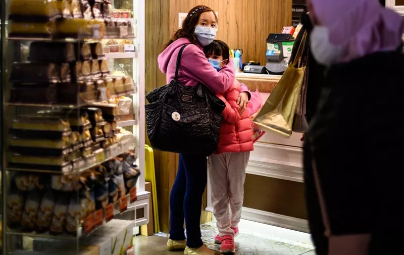 People wearing face masks inside a bakery react as residents in Mei Foo district protest against government plans to convert the Jao Tsung-I Academy a local heritage site into a quarantine camp amid the outbreak of the novel coronavirus which began in the central Chinese city of Wuhan, in Hong Kong on February 2, 2020. - A virus similar to the SARS pathogen has killed more than 300 people in China and spread around the world since emerging in a market in the central Chinese city of Wuhan. (Photo by Philip FONG / AFP)