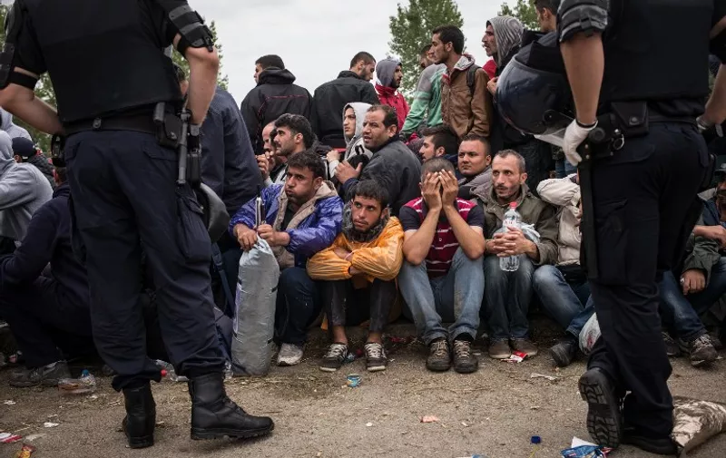 Croatian police officers stand by as people wait to enter the Opatovac transit center for migrants and refugees on September 22, 2015. Croatian Prime Minister Zoran Milanovic urged Serbia on September 22 to restart directing migrants to Hungary and Romania to help ease the burden on his own country. AFP PHOTO / FEDERICO SCOPPA