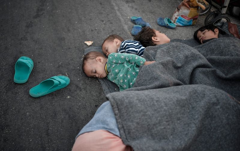 Children rest as they spend the night on the road near Mytilene after a fire destroyed Greece's largest Moria refugee camp on the island of Lesbos, early on September 10, 2020. Greek authorities on September 10 were racing to shelter thousands of asylum seekers left homeless on Lesbos after the island's main migrant camp was gutted by back-to-back fires, which destroyed the official part of the camp housing 4,000 people. Another 8,000 lived in tents and makeshift shacks around the perimeter and many were badly damaged.,Image: 557181372, License: Rights-managed, Restrictions: , Model Release: no