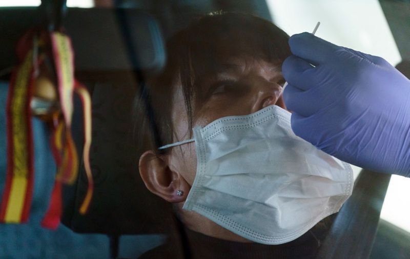 A healthcare worker takes samples from a driver at a drive-through testing point for the COVID-19 disease at the University Hospital in Burgos on March 28, 2020. - The death toll from coronavirus in Spain surged over 5,600 today after a record 832 people died in 24 hours, and the number of infections soared over 72,000, the government said.  Spain has the world's second-highest coronavirus death toll after Italy with 5,690 fatalities. The number of confirmed cases have jumped to 72,248 as the country moves to significantly increase testing. (Photo by CESAR MANSO / AFP)
