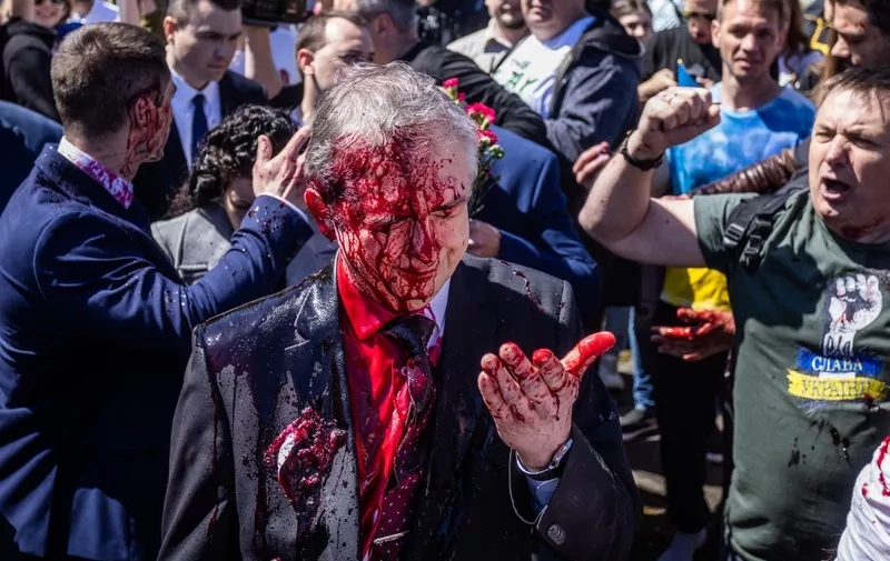 Russian Ambassador to Poland, Ambassador Sergey Andreev reacts after being covered with red paint during a protest prior a ceremony at the Soviet soldier war mausoleum in Warsaw, Poland on May 9, 2022, on the day of the 77th anniversary of the 1945 Soviet victory against Nazi Germany. (Photo by Wojtek RADWANSKI / AFP)