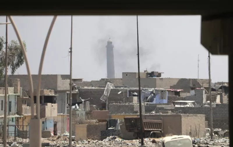 A general view shows smoke rising near Mosul's landmark leaning Al-Hadba minaret oin the Al-Nuri mosque compound, as Iraqi government forces advance in the city's western Zanjili neighbourhood on June 7, 2017, during ongoing battles against Islamic State (IS) group fighters. / AFP PHOTO / KARIM SAHIB