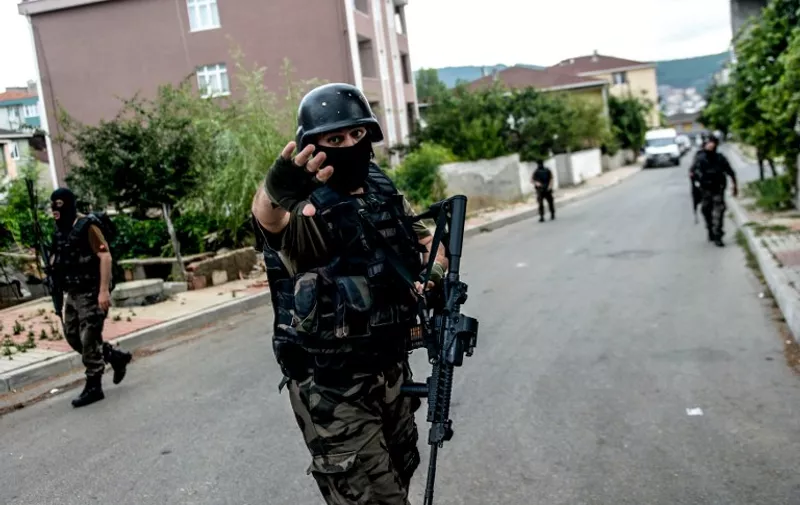 Turkish special force police officers take cover during clashes with attackers on August 10, 2015 at the Sultanbeyli district in Istanbul. Turkey's largest city Istanbul was Monday shaken by twin attacks on the US consulate and a police station as tensions spiral amid the government's air campaign against Kurdish militants. AFP PHOTO / OZAN KOSE / AFP / OZAN KOSE