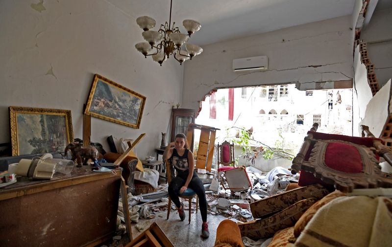 A woman sits amidst the rubble in her damaged house in the Lebanese capital Beirut on August 6, 2020, two days after a massive explosion shook the Lebanese capital. - The blast, which appeared to have been caused by a fire igniting 2,750 tonnes of ammonium nitrate left unsecured in a warehouse, was felt as far away as Cyprus, some 150 miles (240 kilometres) to the northwest. The scale of the destruction was such that the Lebanese capital resembled the scene of an earthquake, with thousands of people left homeless and thousands more cramming into overwhelmed hospitals for treatment. (Photo by - / AFP)
