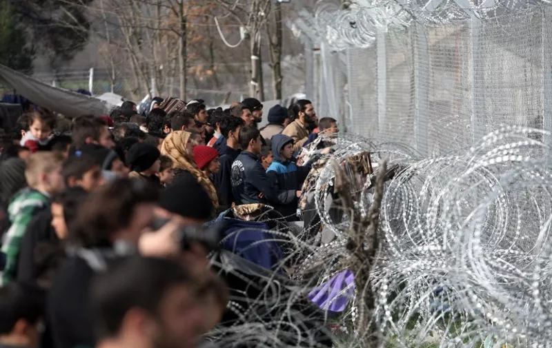 Migrants and refugees wait to cross the Greece-Macedonia border near the village of Idomeni, on 1 March, 2016. 
Macedonian police fired tear gas as some 300 migrants forced their way through a Greek police cordon and raced towards a railway track between the two countries on February 29, 2016. With Austria and Balkan states capping the numbers of migrants entering their soil, there has been a swift buildup along the Greek - Macedonian border with Athens warning that the number of people "trapped" could reach up to 70,000 by next month.   / AFP / SAKIS MITROLIDIS