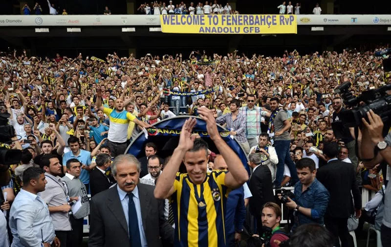 Manchester Uniteds international striker Dutch Robin Van Persie (C) flanked by Fenerbahce's Italian Sports Director Giuliano Terraneo (CL) applauds to Fenerbahce's fans during a signing ceremony with the Turkish Super Lig giants football club Fenerbahce at the Sukru Saracoglu stadium in Istanbul on July 14, 2015. The Dutch international is believed to have put pen to paper on a three-year deal worth 4.7 million euros (£3.4m, $5.2m) although financial details have yet to be disclosed.
 AFP PHOTO/ OZAN KOSE