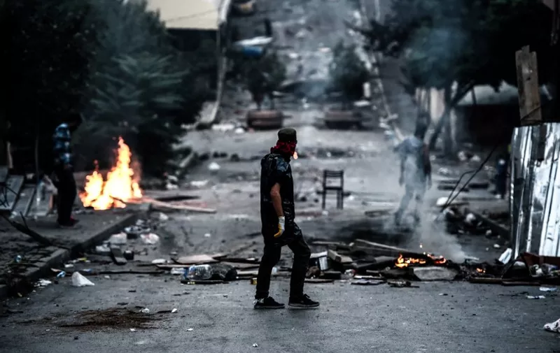 A left-wing protester waits in front of a barricade during clashes with Turkish riot police in the district of Gazi in Istanbul, on July 26, 2015. A Turkish policeman was killed on July 26, 2015 during clashes with protesters in the flashpoint Istanbul district of Gazi which have raged for the last three days following the death of a leftist activist during raids by the security forces. Turkey has launched a two-pronged "anti-terror" cross-border offensive against Islamic State (IS) jihadists and Kurdistan Workers Party (PKK) militants after a wave of violence in the country, pounding their positions with air strikes and artillery. But the expansion of the campaign to include not just IS targets in Syria but PKK rebels in neighbouring northern Iraq -- themselves bitterly opposed to the jihadists -- has put in jeopardy a truce with the Kurdish militants that has largely held since 2013. AFP PHOTO / OZAN KOSE