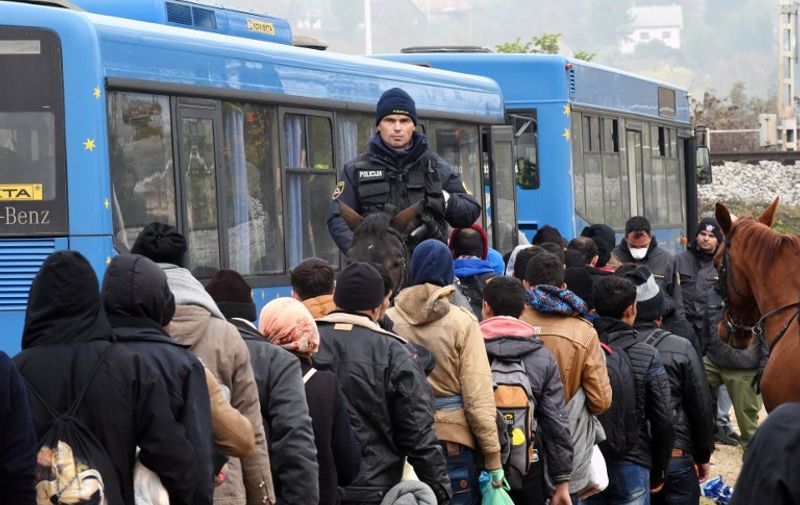 A Slovenian mounted police officer escorts migrants and asylum seekers as they queue to board buses bound for a registration camp in Brezice after crossing the Croatian-Slovenian border near Rigonce on October 27, 2015. More than 700,000 refugees and migrants have reached Europe's Mediterranean shores so far this year, amid the continent's worst migration crisis since World War II, the UN refugee agency said. AFP PHOTO / STRINGER