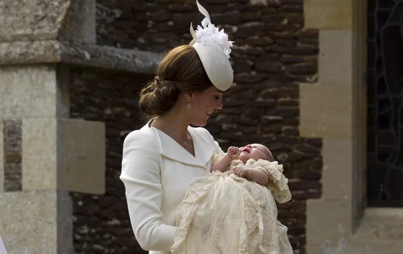 Britain's Catherine, Duchess of Cambridge, carries her daughter, Princess Charlotte of Cambridge after taking her out of a pram as they arrive for Charlotte's Christening at St. Mary Magdalene Church in Sandringham, England, on July 5, 2015. Crowds gathered outside Queen Elizabeth II's country residence on Sunday for the christening of Britain's baby Princess Charlotte, who it was announced will have five godparents. AFP PHOTO / POOL / MATT DUNHAM