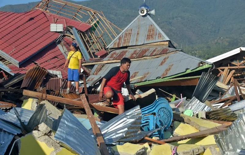 People inspect damaged houses in Palu, Indonesia's Central Sulawesi on October 1, 2018, after an earthquake and tsunami hit the area on September 28.
Indonesian volunteers began burying bodies in a mass grave with space for more than a thousand people on October 1, victims of a quake-tsunami that devastated swathes of Sulawesi and left authorities struggling to deal with the sheer scale of the disaster. / AFP PHOTO / Adek BERRY