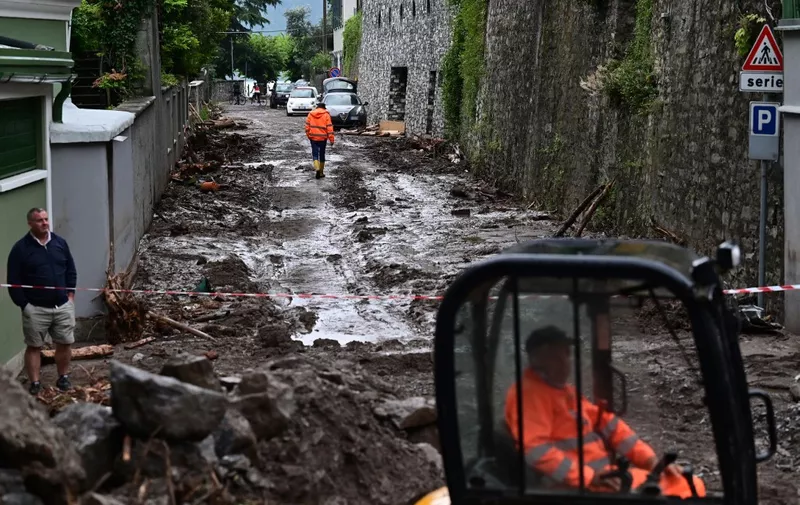 A worker uses an excavator to clear the damages caused by a landslide in Laglio after heavy rain caused floods in towns surrounding Lake Como in northern Italy, on July 28, 2021. (Photo by MIGUEL MEDINA / AFP)