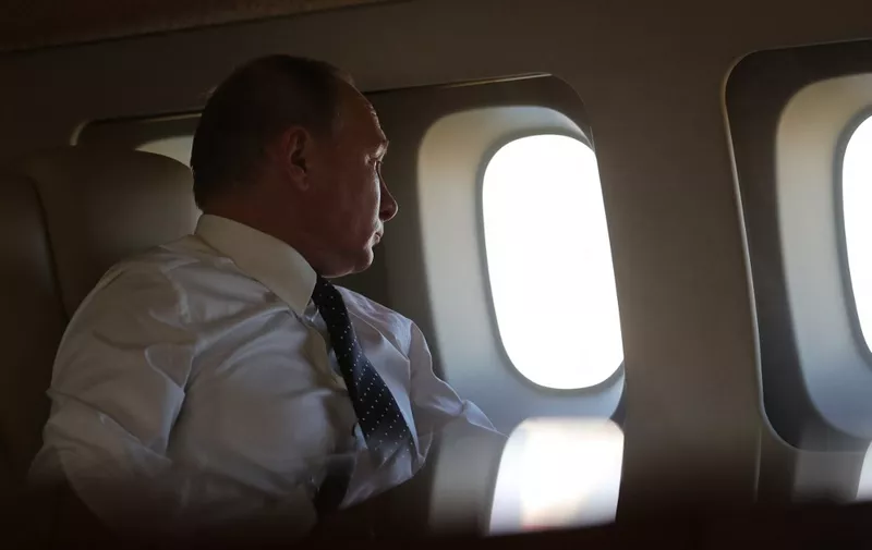 Russian President Vladimir Putin looks through the porthole while aboard the presidential plane during the approach to the Russian air base in Hmeimim in the northwestern Syrian province of Latakia on December 11, 2017. - Russian news agencies reported that Putin gave an order for partial withdrawal of Russian troops from Syria during a press conference at Hmeimim on December 11. (Photo by Mikhail KLIMENTYEV / POOL / AFP)