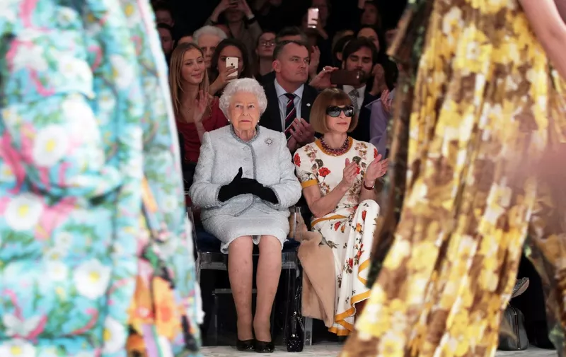 Britain's Queen Elizabeth II, accompanied by British-American journalist and editor, Anna Wintour (R), views British designer Richard Quinn's runway show before presenting him with the inaugural Queen Elizabeth II Award for British Design, during her visit to London Fashion Week's BFC Show Space in central London on February 20, 2018. (Photo by Yui Mok / POOL / AFP)