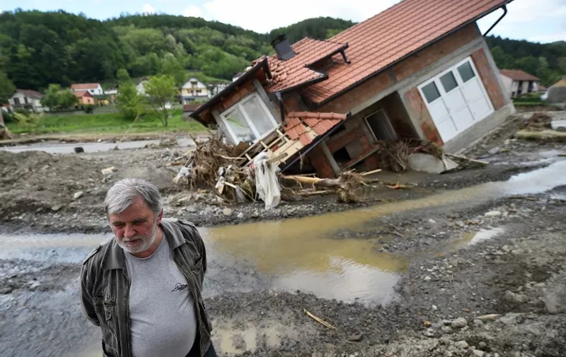 A man stands near house damaged by flooding and landslides in Krupanj, some 130 kilometres south west of Belgrade, on May 20, 2014, after the western Serbian town was hit with floods and landslides, cutting it off for four days. Serbia declared three days of national mourning on May 20 as the death toll from the worst flood to hit the Balkans in living memory rose and health officials warned of a possible epidemic. At least 49 people have been killed already by the worst floods in central Europe for a century and more than 1.6 million people have been hit as the river Sava and its tributaries have burst their banks, inundating tens of thousands of hectares of farmland and destroying houses and buildings.   AFP PHOTO / ANDREJ ISAKOVIC / AFP / ANDREJ ISAKOVIC