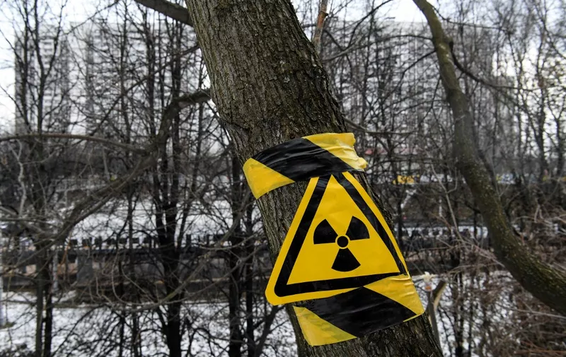 A radiation sign is seen at a tree on the hill, which contains radioactive waste buried in the pre-Chernobyl Soviet era, near the spot where a new eight-lane highway is planned in Moscow on February 17, 2020. Andrei Ozharovsky suspends a selfie stick holding a dosimeter-equipped smartphone over a shallow dip in the thawing ground. The contraption crackles and pops as the displayed figure increases -- underlining the concerns of local residents over the plan to build an eight-lane highway in an area containing radioactive waste buried in the pre-Chernobyl Soviet era. (Photo by Kirill KUDRYAVTSEV / AFP)