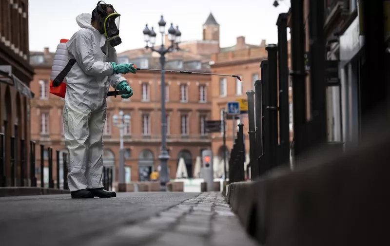 A municipal worker wearing protections sprays disinfectant products in the street of Toulouse, southern France on April 6, 2020, on the 21st day of a strict nationwide confinement in France seeking to halt the spread of the COVID-19 infection caused by the novel coronavirus. (Photo by Lionel BONAVENTURE / AFP)