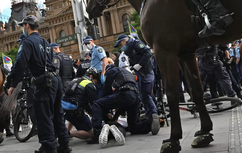 Police detains a protester during an anti-lockdown rally in Sydney on July 24, 2021, as thousands of people gathered to demonstrate against the city's month-long stay-at-home orders. (Photo by Steven SAPHORE / AFP)
