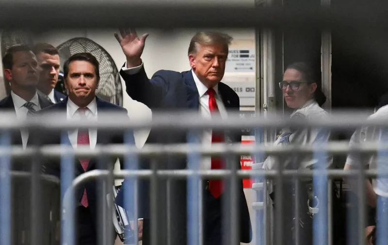Former US President Donald Trump waves as he returns to the courtroom after a break during the first day of his trial for allegedly covering up hush money payments linked to extramarital affairs, at Manhattan Criminal Court in New York City on April 15, 2024. Trump is in court Monday as the first US ex-president ever to be criminally prosecuted, a seismic moment for the United States as the presumptive Republican nominee campaigns to re-take the White House. The scandal-plagued 77-year-old is accused of falsifying business records in a scheme to cover up an alleged sexual encounter with adult film actress Stormy Daniels to shield his 2016 election campaign from adverse publicity. (Photo by ANGELA WEISS / POOL / AFP)