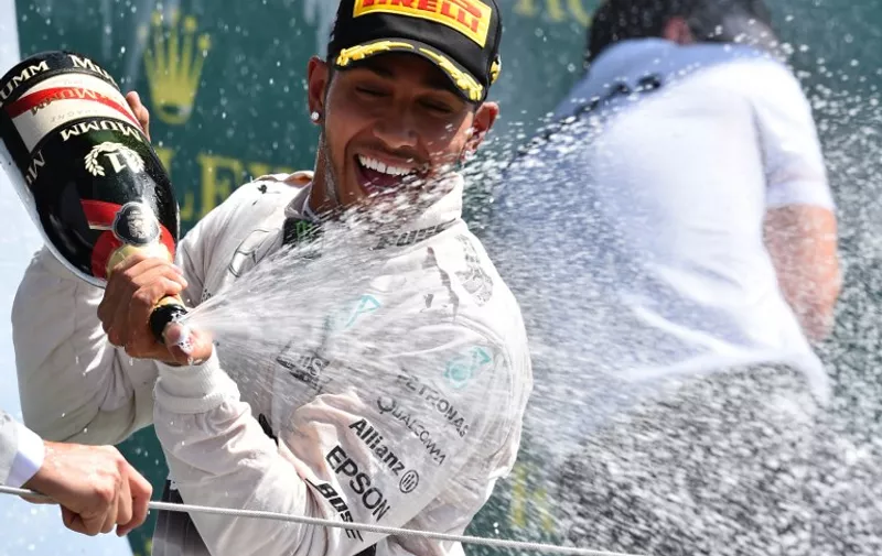 Mercedes AMG Petronas F1 Team's British driver Lewis Hamilton celebrates on the podium after winning the British Formula One Grand Prix at the Silverstone circuit in Silverstone on July 5, 2015.
 AFP PHOTO / BEN STANSALL